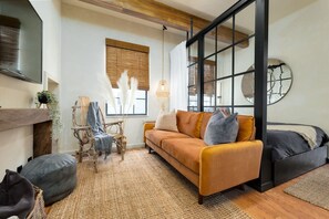 A modern living room with a sofa, chairs, a fireplace, and a large window with blinds. - Wabi-Sabi Inspired Studio w Bikes, Walk to River (Jacksonville)