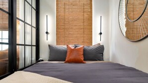 A modern bedroom with a large bed, a window with blinds, and a round mirror on the wall. - Wabi-Sabi Inspired Studio w Bikes, Walk to River (Jacksonville)