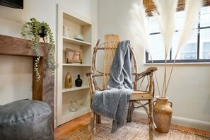 A rustic wooden chair with a grey throw blanket, a woven rug, and a vase with dried plants. - Wabi-Sabi Inspired Studio w Bikes, Walk to River (Jacksonville)