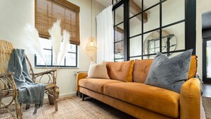 Una sala de estar con un sofá, una silla y un tapete tejido.