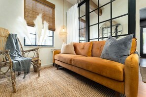 A living room with a sofa, a chair, and a woven rug.