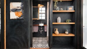 Un baño moderno con piso de baldosas blanco y negro, un lavamanos blanco y una lámpara colgante.