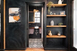 A modern bathroom with a black and white tiled floor, a white sink, and a hanging light fixture.