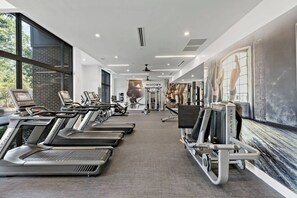 Un gimnasio con cintas de correr, bicicletas estáticas y máquinas de pesas.