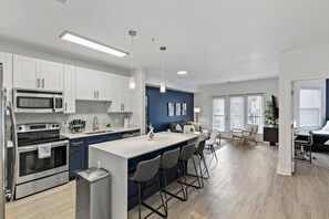 Una cocina moderna con una isla central, electrodomésticos integrados y una zona de comedor con taburetes de bar.