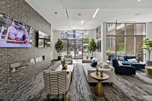 Un moderno vestíbulo de hotel con televisor, zona de estar y grandes ventanales.