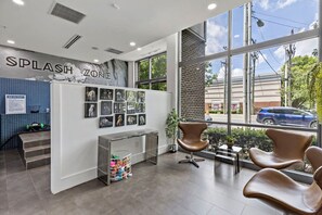 A dog grooming salon interior with a 'Splash Zone' sign, a wall of dog photos, a reception desk, and a large window offering a view of the street. - Near DT  CPCC Lynx with  Pool Gym WD Parking (Charlotte)