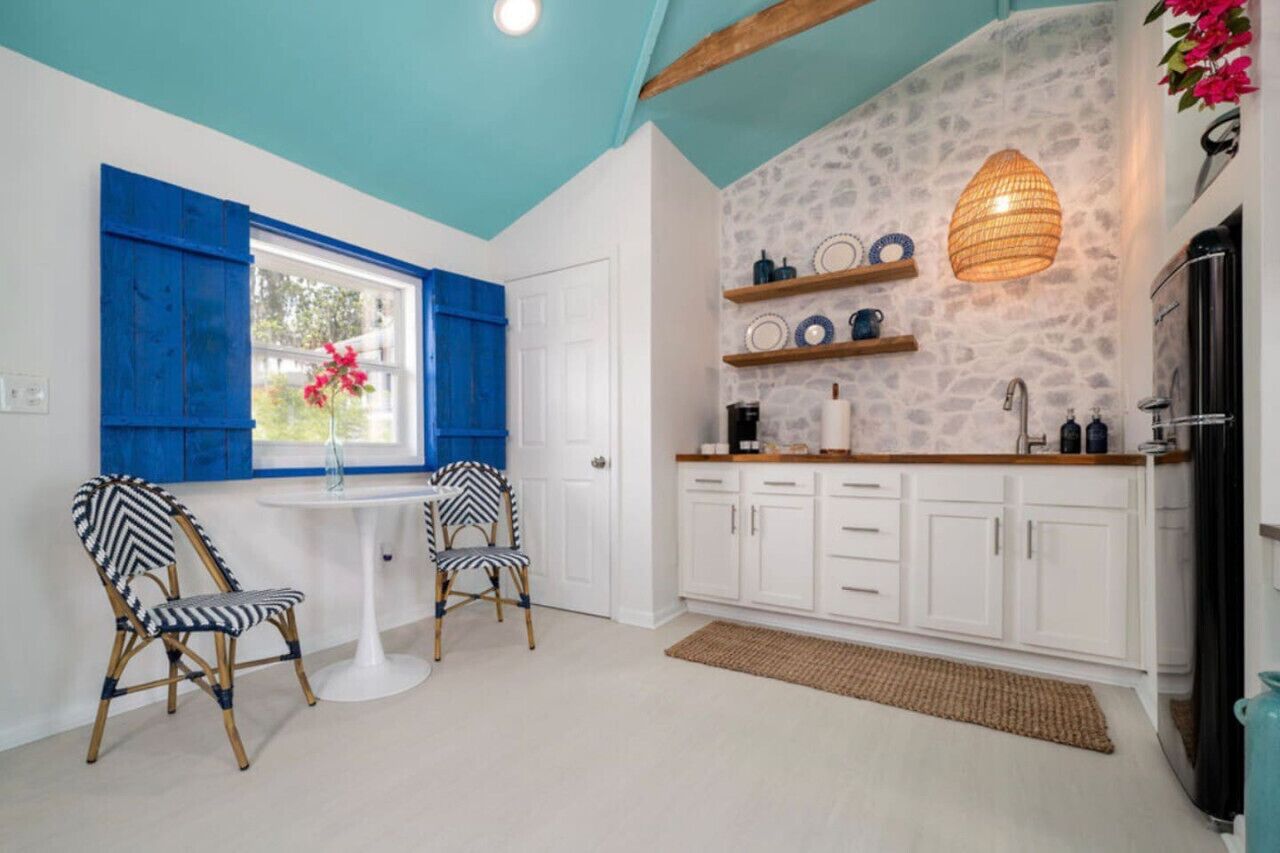 A kitchen with white cabinets, a white countertop, and a hanging light fixture.