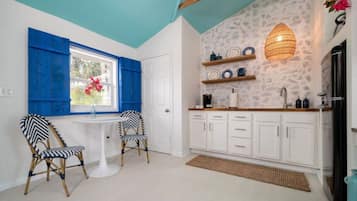 A kitchen with white cabinets, a white countertop, and a hanging light fixture.
