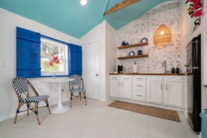 Una cocina con armarios blancos, encimera blanca y una lámpara colgante.