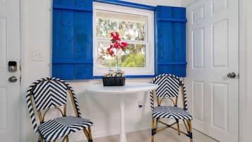 A room with two chairs, a small table, and a window with blue shutters.