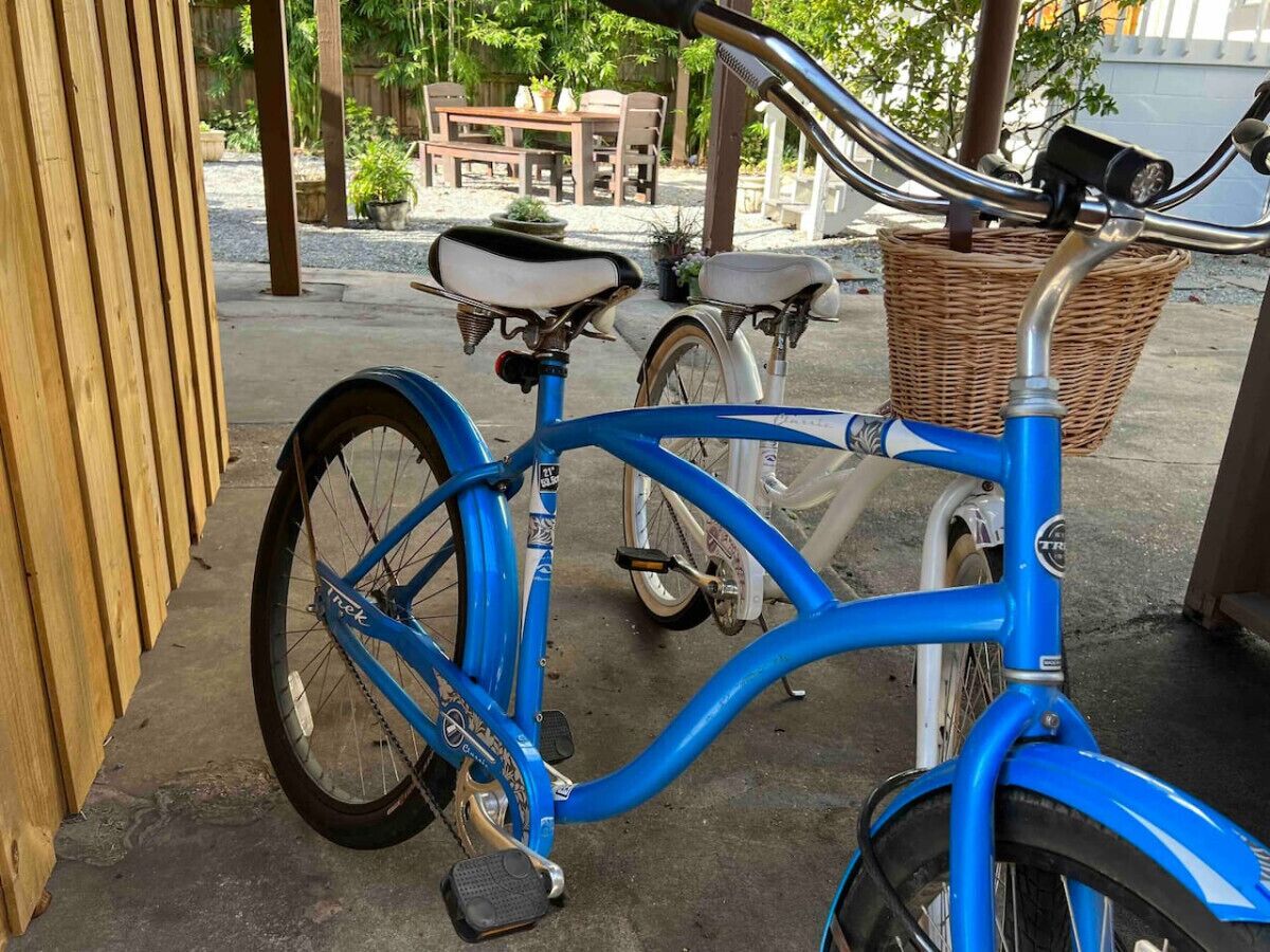 A blue bicycle parked on a concrete surface with a wicker basket attached to the back.
