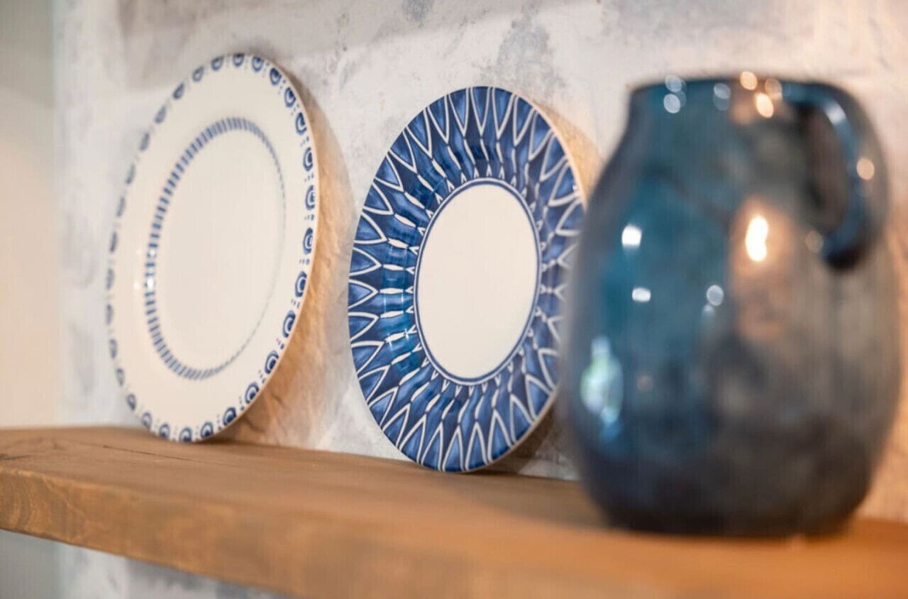 Tre oggetti in ceramica su uno scaffale, con una parete strutturata sullo sfondo.