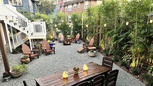 Een houten terras met een tafel en stoelen, omgeven door potplanten en een bamboomschutting.
