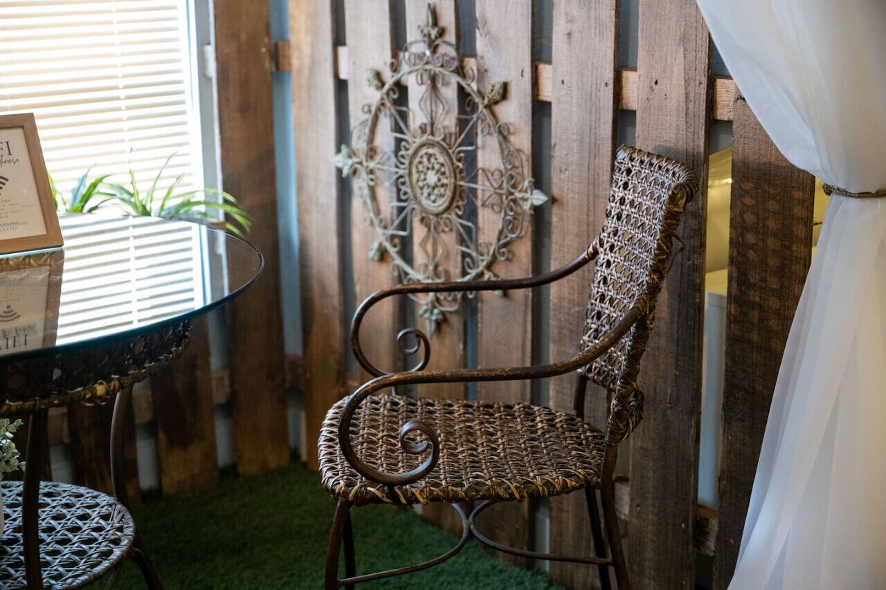 Una silla de mimbre con estructura metálica, un adorno metálico en la pared y una mesa con un menú.