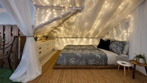 Een slaapkamer met een hemelbed, nachtkastje en nachttafel.