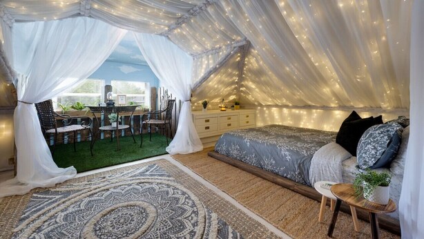 Een interieur met een bed, een tafeltje en een zithoek met stoelen.