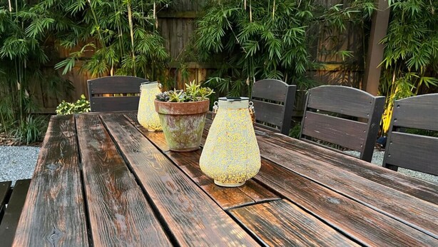 Ein Holztisch für ein Picknick mit Metall-Pflanzgefäßen und einer Zierlampe.