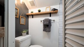 Een kleine badkamer met toilet, een handdoekhouder en een plank met decoratieve spullen.