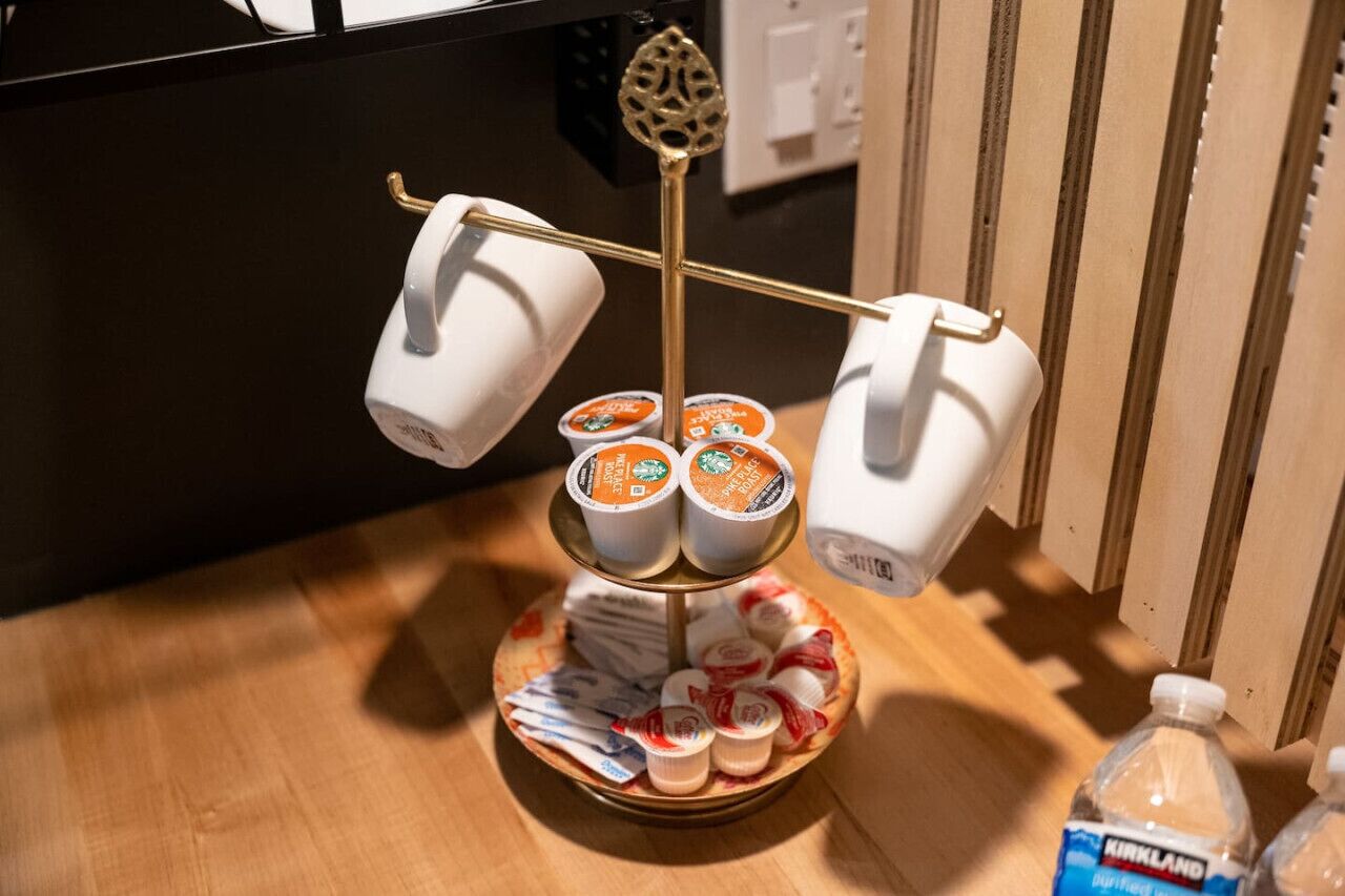 Un plateau contenant plusieurs tasses et une bouteille d’eau, posé sur une surface en bois.
