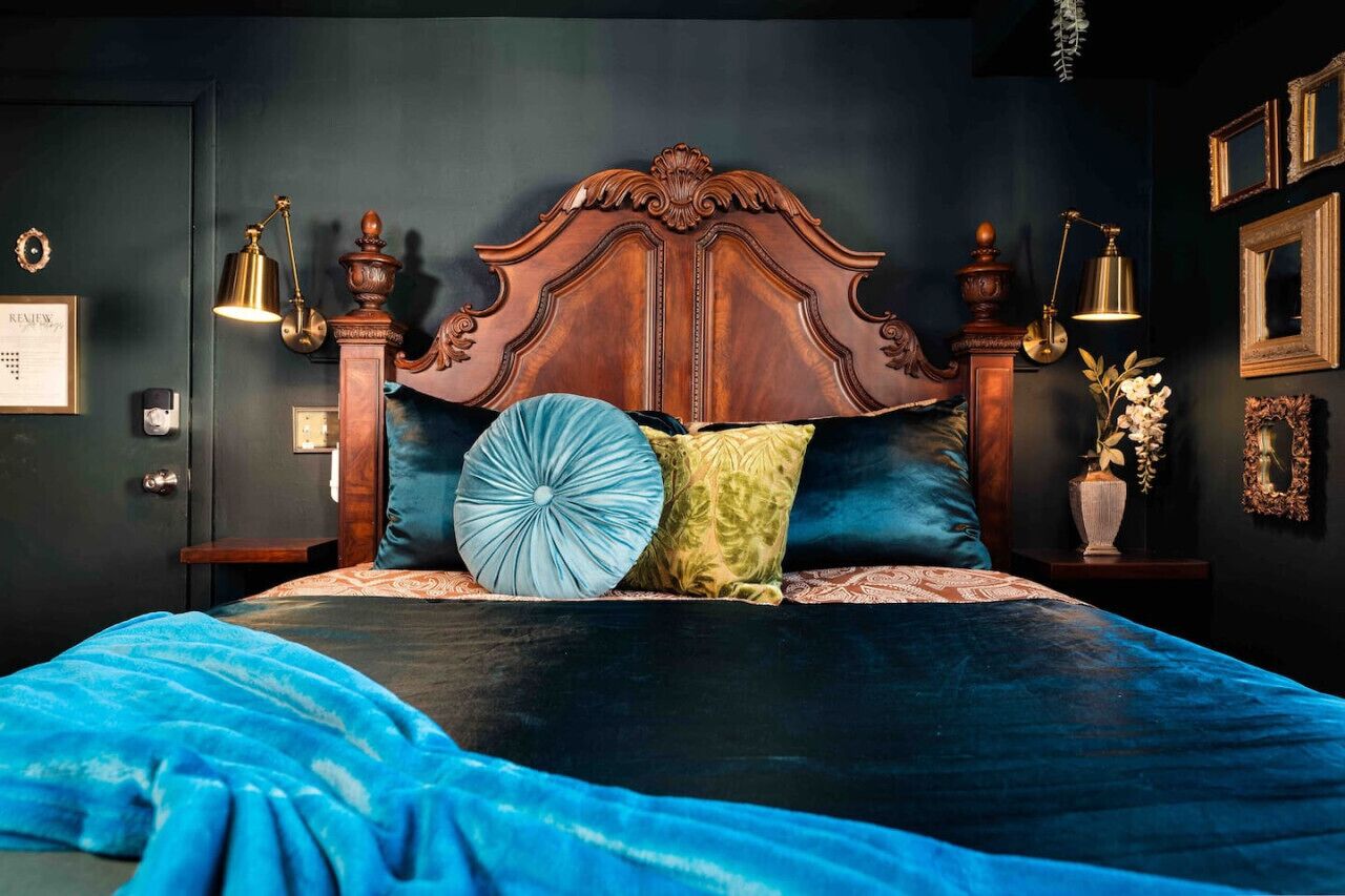 A bedroom with a large bed, ornate wooden headboard, and multiple pillows.