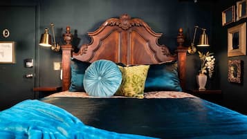A bedroom with a large bed, ornate wooden headboard, and multiple pillows.