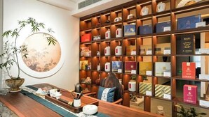 Una zona de recepción con un mostrador de madera, un gran tapiz circular en la pared y una estantería con diversos objetos.