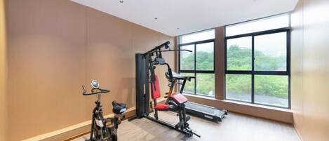 A gym with exercise equipment, large windows, and a view of greenery.