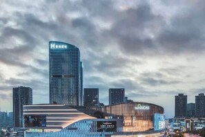Un hotel moderno con fachada curva, un llamativo letrero del hotel H y una gran pantalla digital que muestra el nombre del hotel.