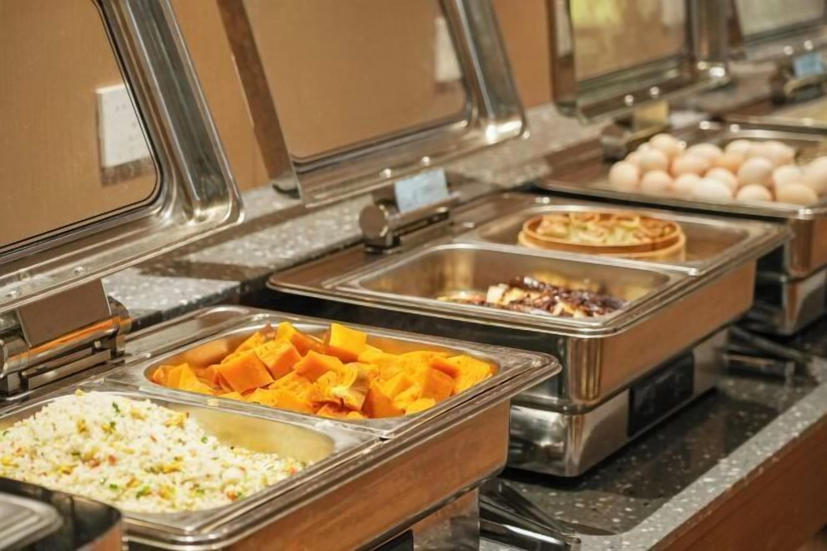 Un bufé con diversas opciones de comida, como arroz, gajos de naranja y un pastel.