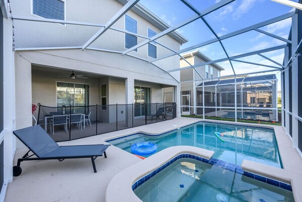 An indoor swimming pool with a glass ceiling, lounge chairs, and a table with chairs. - Near Disney Beautiful Champions Retreat home, Private Pool Spa, BBQ, Game room (Four Corners)