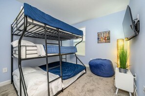 A bunk bed room with a TV, a plant, and a painting on the wall. - Near Disney Beautiful Champions Retreat home, Private Pool Spa, BBQ, Game room (Four Corners)