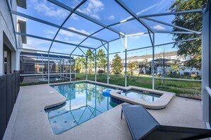 A covered outdoor swimming pool with a glass enclosure, surrounded by a grassy area and trees. - Near Disney Beautiful Champions Retreat home, Private Pool Spa, BBQ, Game room (Four Corners)