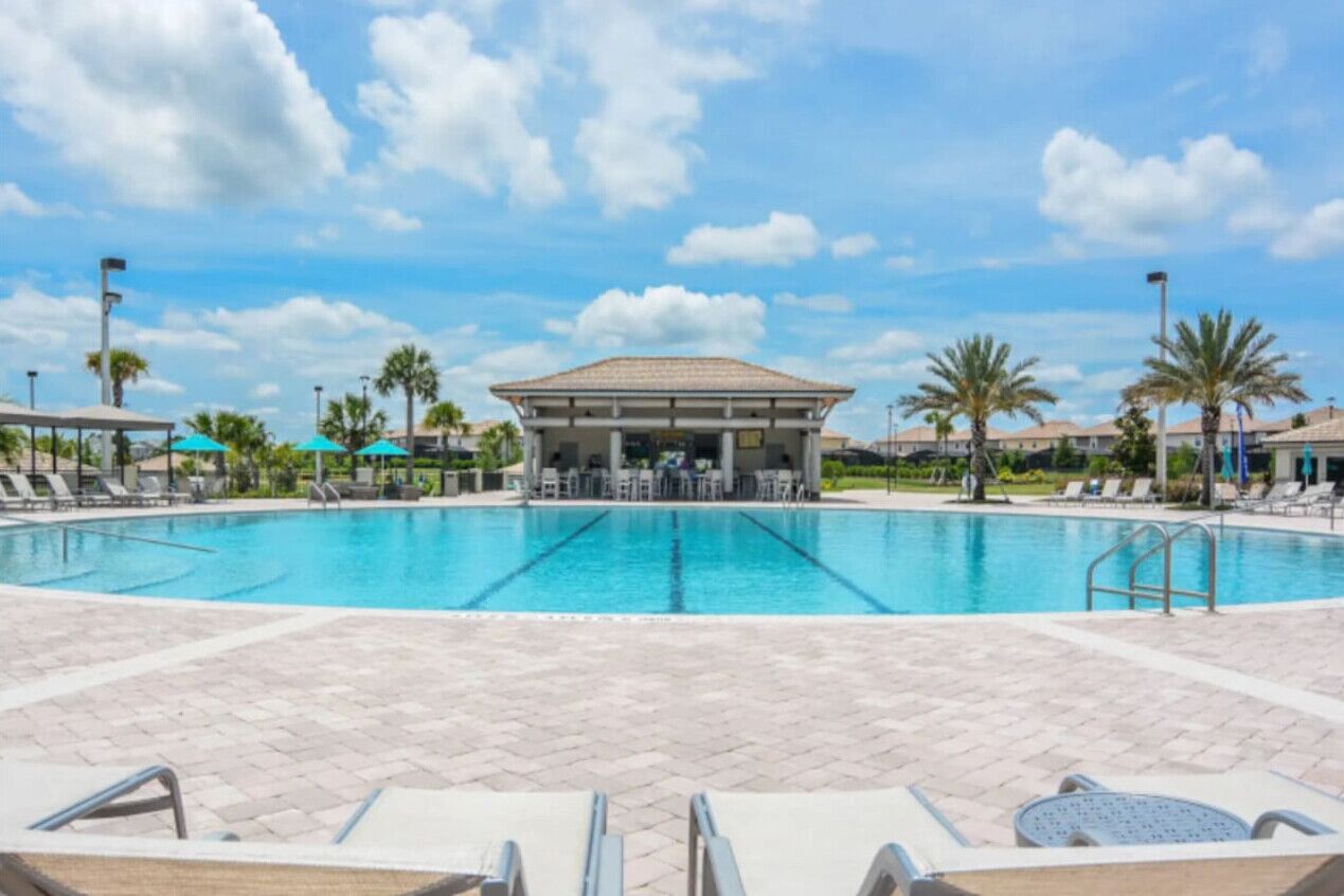 A swimming pool with lounge chairs and a covered seating area.