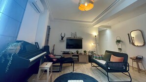 A living room with a piano, a sofa, a coffee table, and a TV. - Aux Nuits de Miel - Marrakech  (Marrakech)