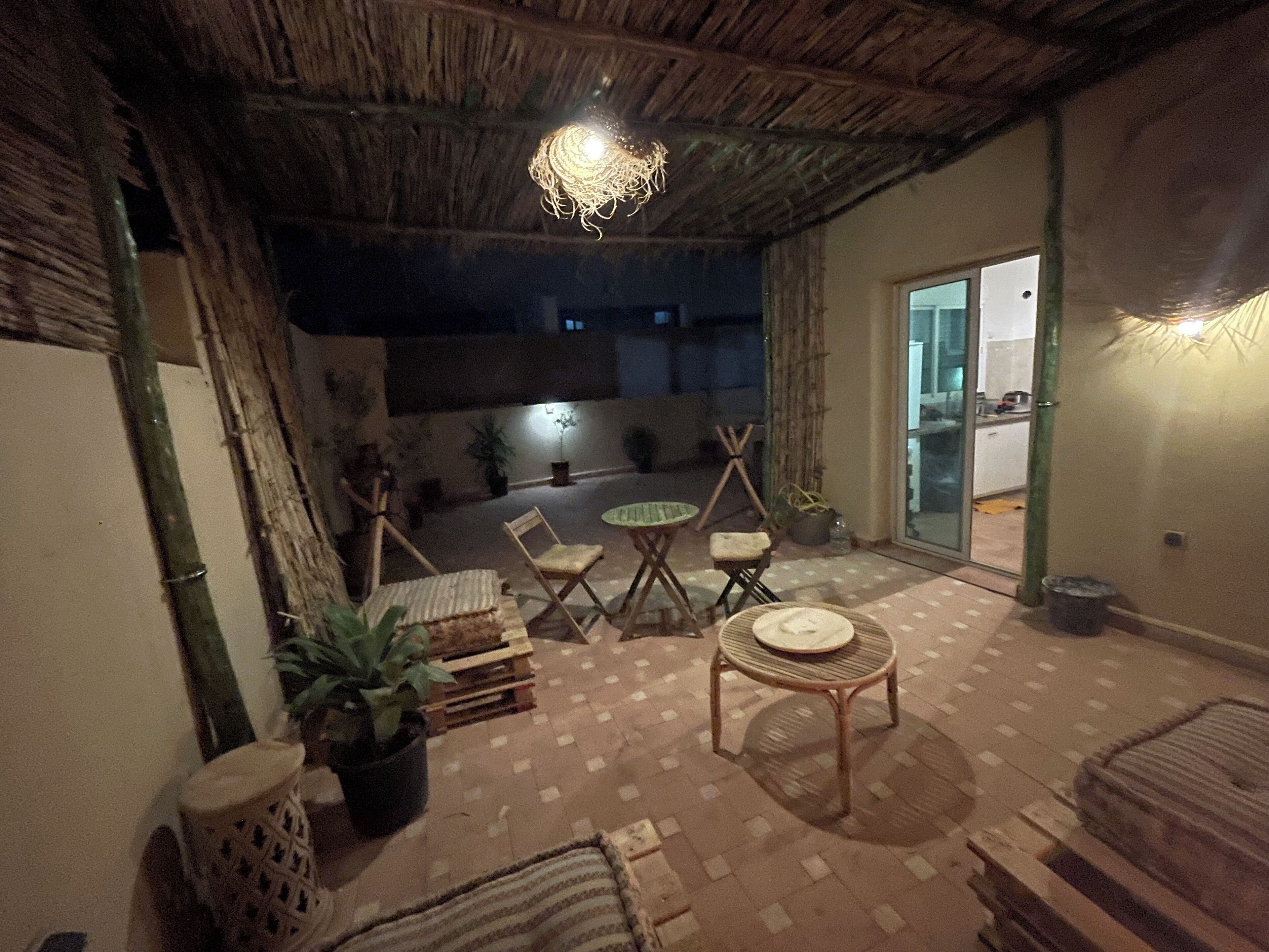 Un patio al aire libre con techo de paja, muebles de madera y plantas en macetas.