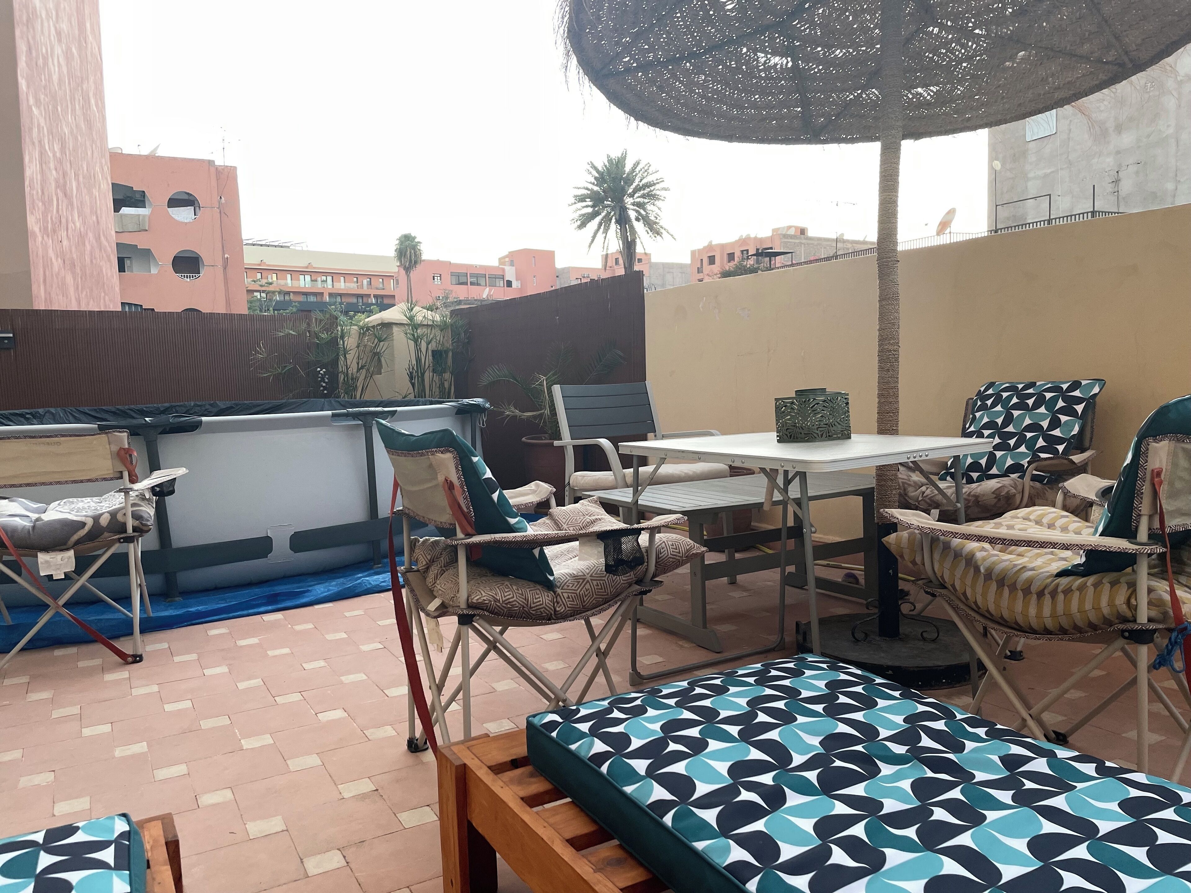 A patio area with a table, chairs, and a patterned sofa.