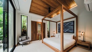 Ein modernes Schlafzimmer mit einem Himmelbett, einer Sitzecke mit einem Sessel und einem großen Fenster.