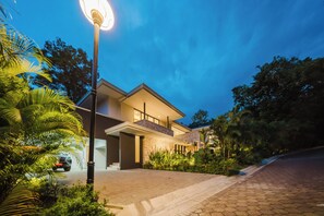 Een modern huis met twee verdiepingen, een verharde oprit en een straatlamp.