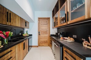 Een moderne keuken met houten kastjes, een zwart aanrecht en een schaal met fruit.