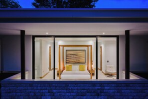 Een moderne slaapkamer met een groot bed, een schilderij aan de muur en een stoel.