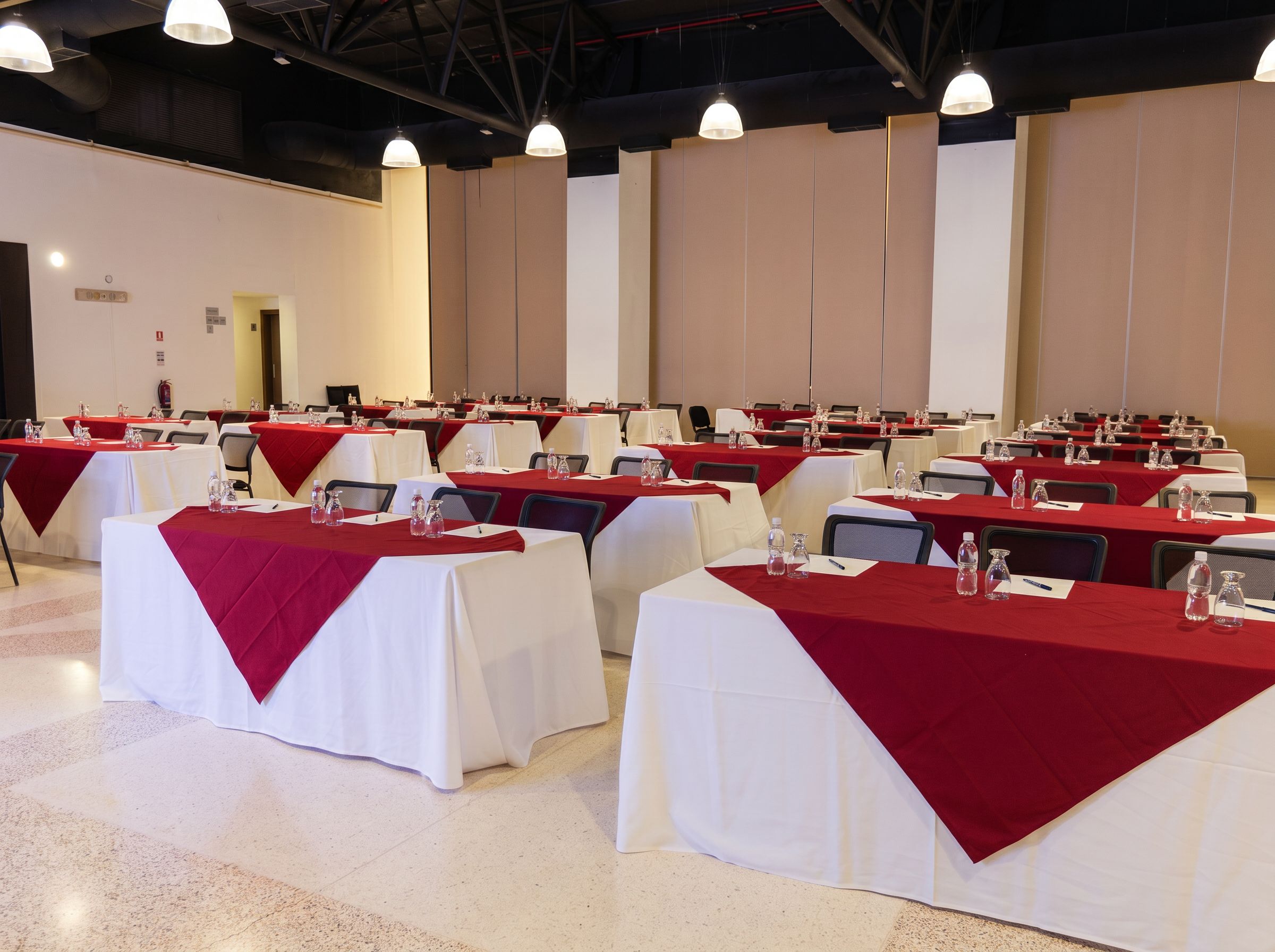Une salle de conférence avec des tables disposées pour les réunions, équipée de bouteilles d’eau et de plaques nominatives.
