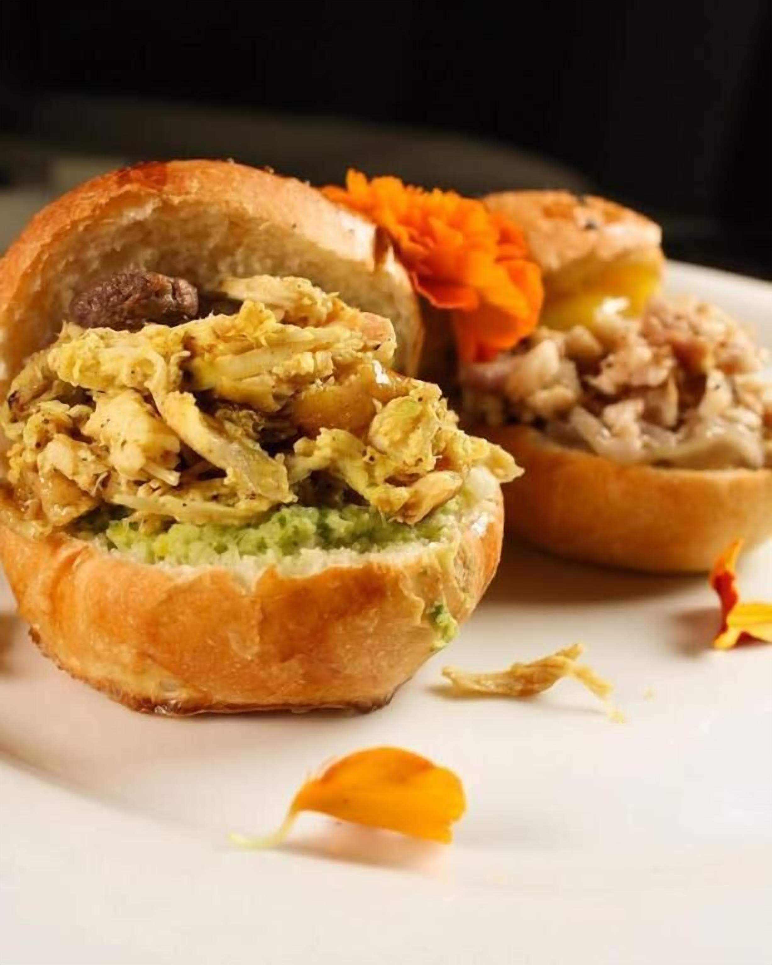 Un sándwich cortado por la mitad, mostrando capas de carne y vegetales en su interior.