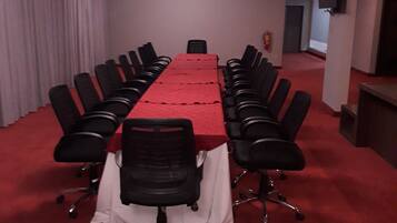 A conference room with a long table, black chairs, and a red carpet.