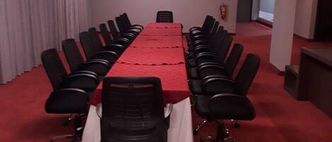 A conference room with a long table, black chairs, and a red carpet.