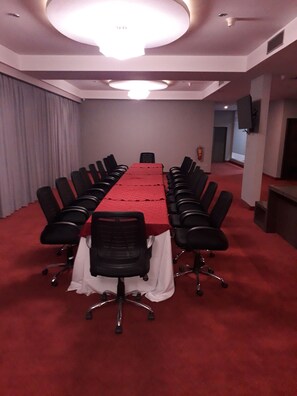 A conference room with a long table, black chairs, and a red carpet. - Hesperia Maracay (Maracay)