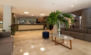 A hotel lobby with a reception desk, seating area, and a staircase. - Hesperia Maracay (Maracay)