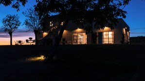 Una casa con un'ampia finestra, un muro in mattoni e un albero di fronte.