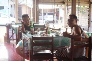 A dining area with a table and chairs, a bottle, and a cup. - Duyung Rooms & Resto Gerupuk (Kuta)