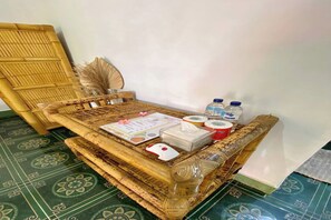 A room with a woven bench, a wall-mounted fan, and a patterned floor. - Duyung Rooms and Resto by Zuzu (Kuta)